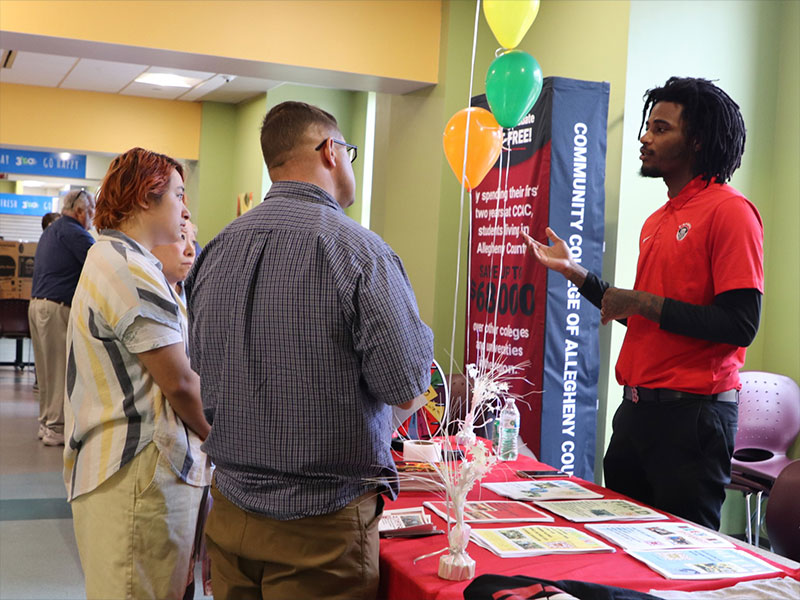 Two attendees discuss CCAC programs at an Open House information table