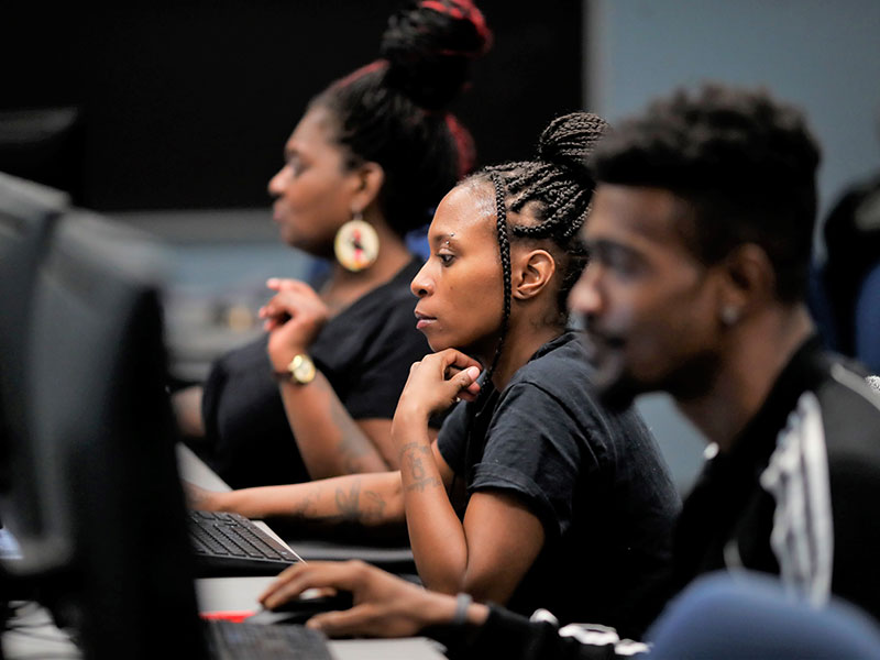 Students work at a row of computers at CCAC.