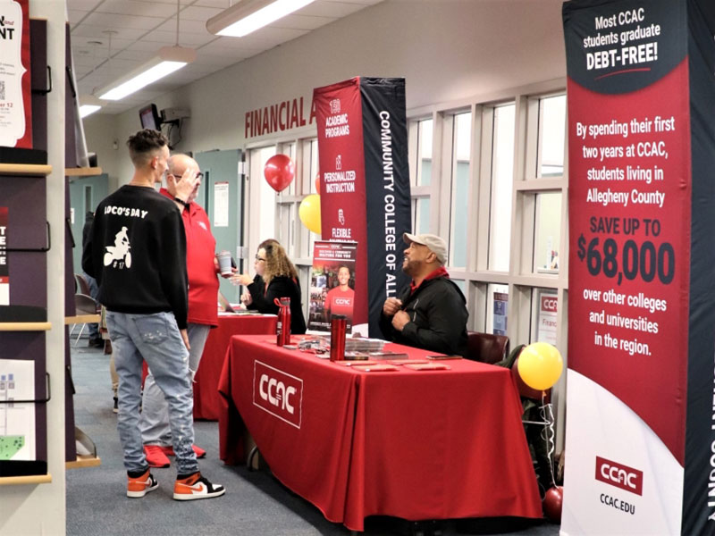 CCAC staff welcome students to an Open House event with informational signs and booths.