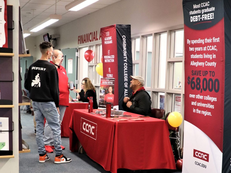 CCAC staff greet students with tables of resources during an Open House event.