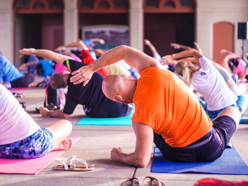A roomful of people stretch in unison during a group yoga class.