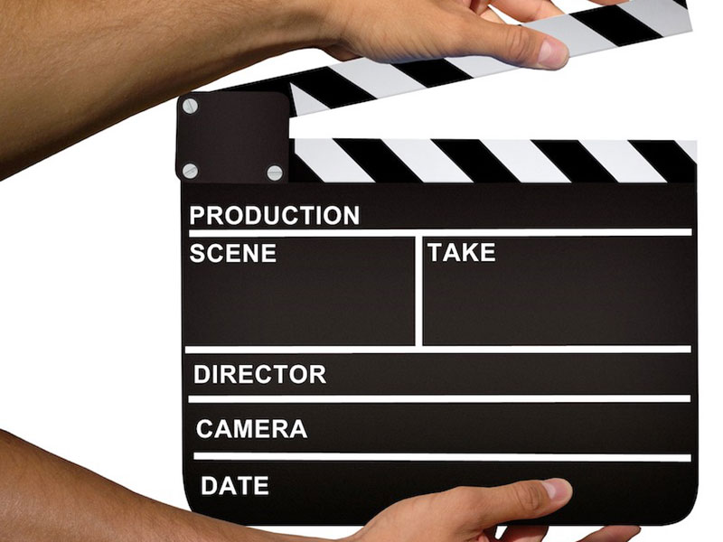 A second assistant cameraman demonstrates how to hold a clapperboard, a piece of equipment used to help synchronize picture and sound when making a movie.